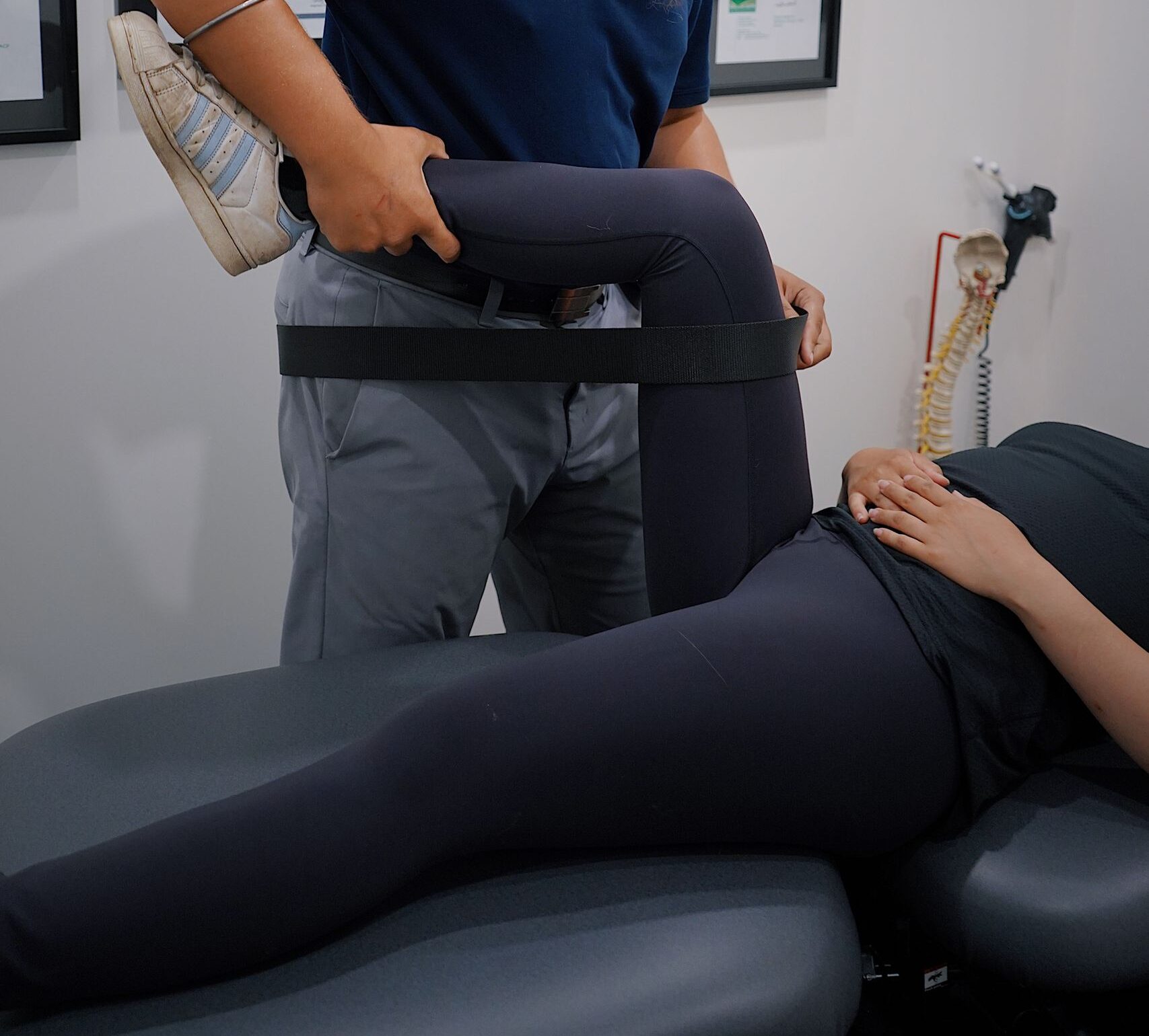 Male physiotherapist with turban helping female patient with leg rehabilitation exercise in a modern clinic setting.
